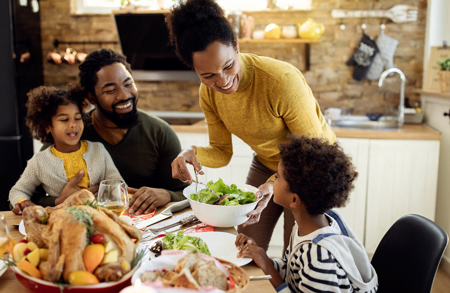 A family laughs as they eat together at the dinner table. 