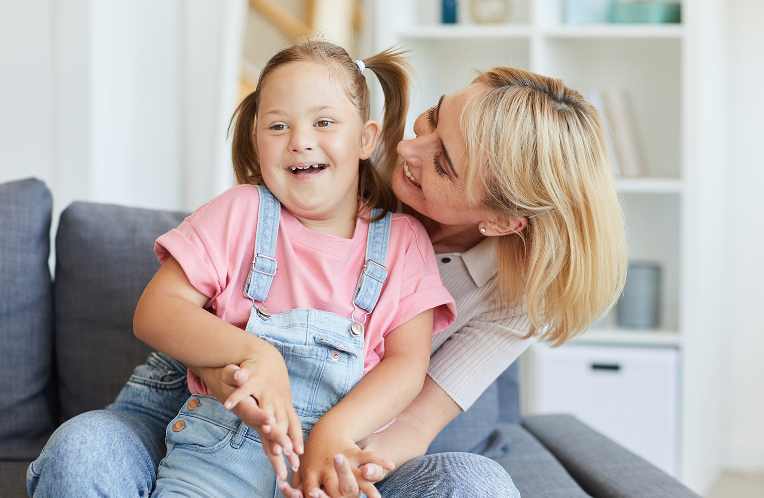 A mother smiles at her daughter who has a disability.