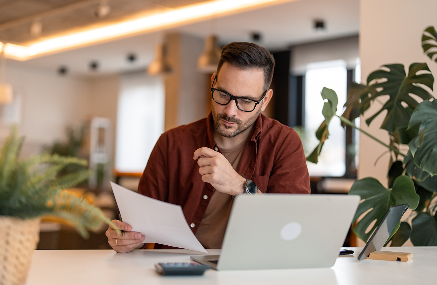 A man studies a paper to evaluate a self-funding health plan.