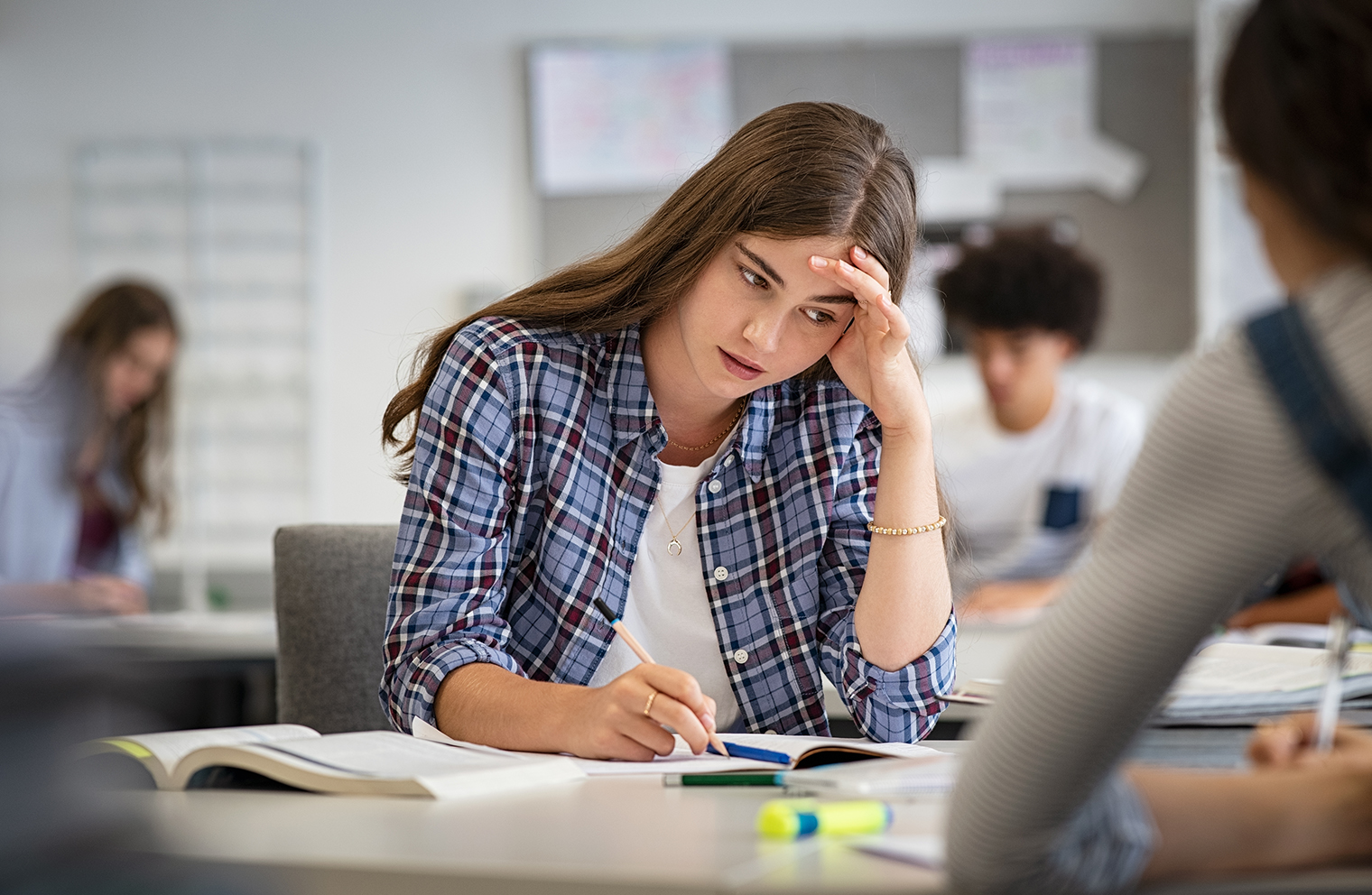 A student is stressed and struggling with back-to-school mental health as she sits at her desk in a classroom. 