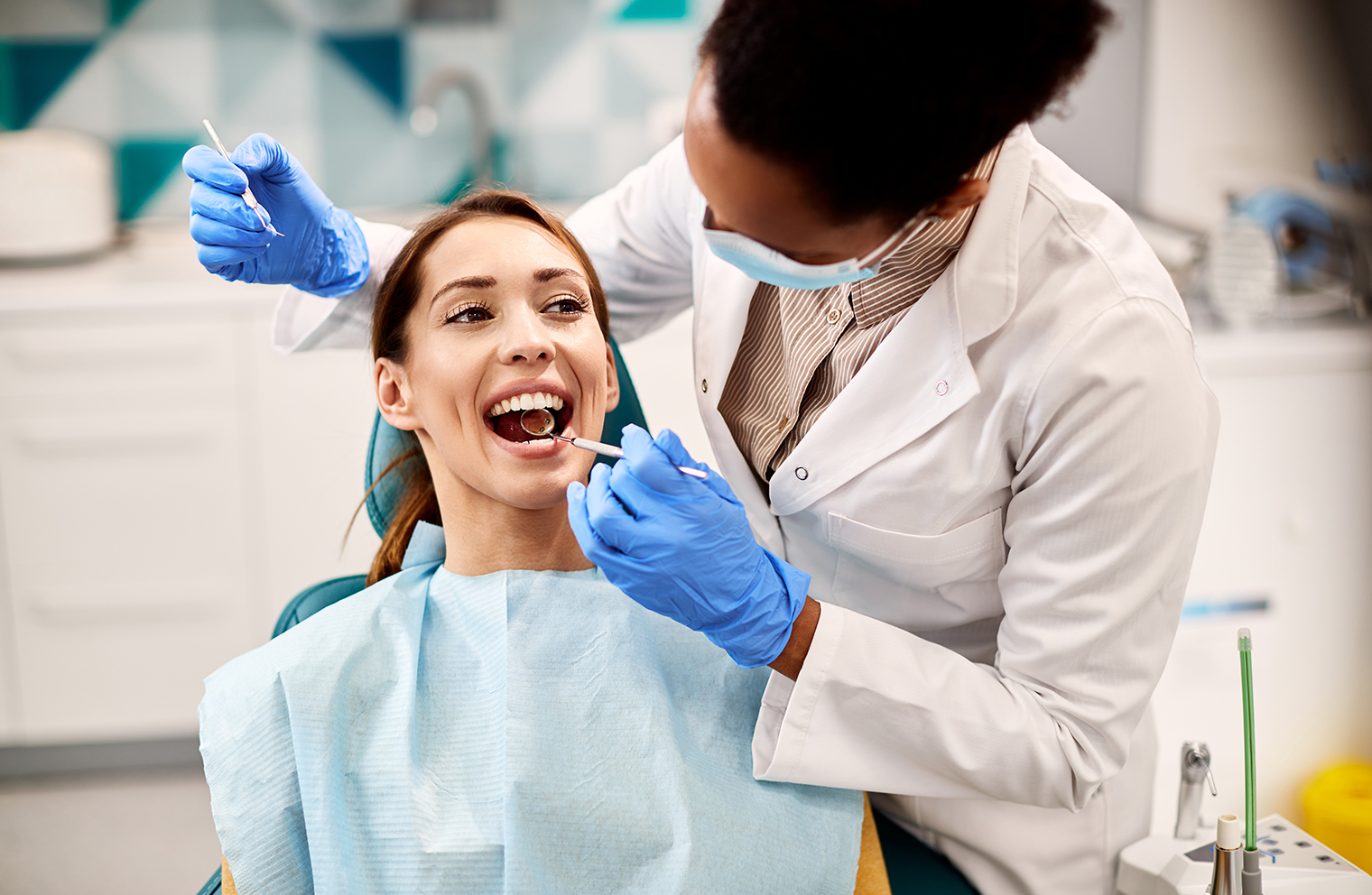 A woman with dental insurance gets her teeth examined by a dentist. 