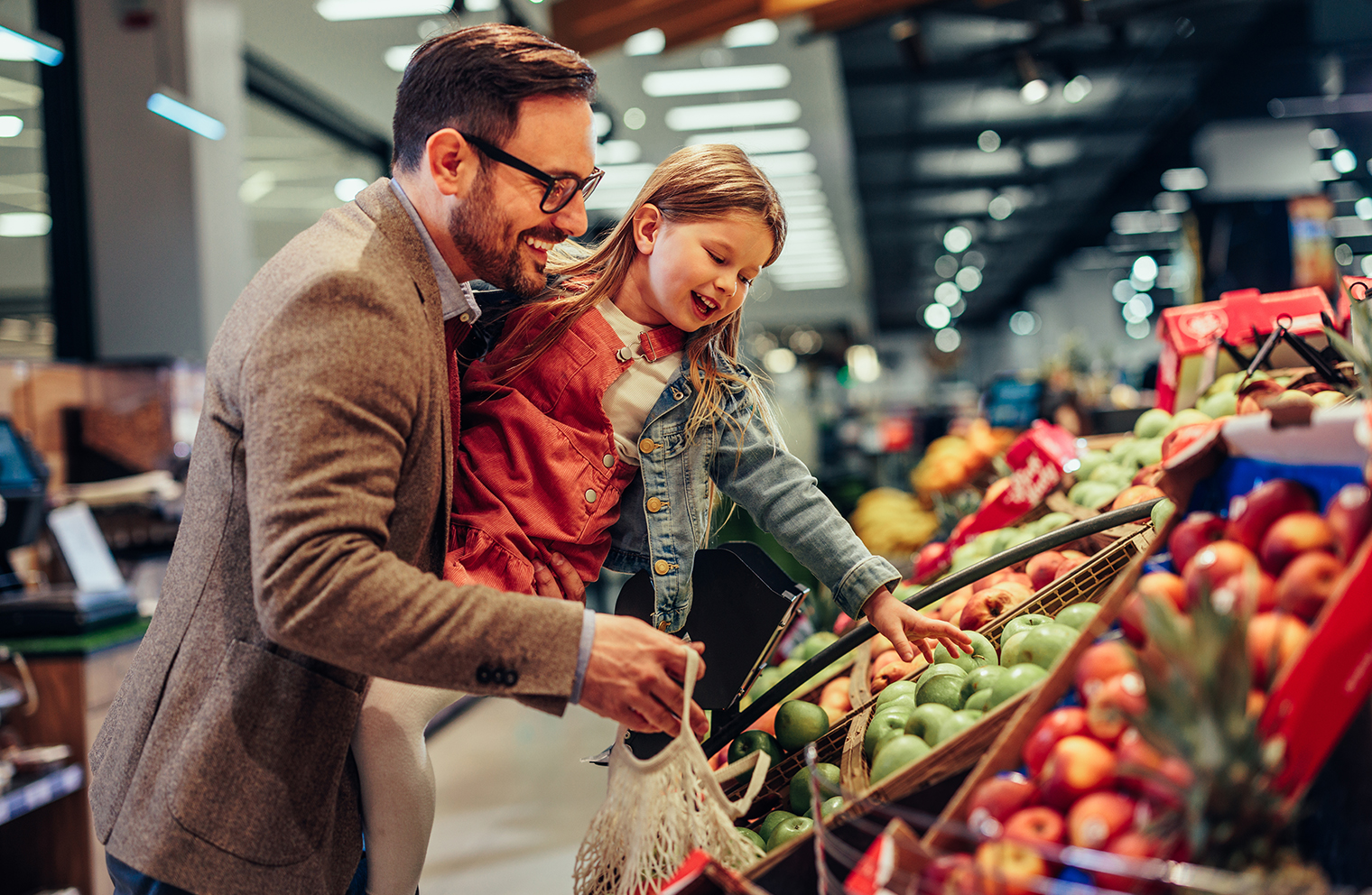A man and his daughter shop for fresh produce in the grocery store. 