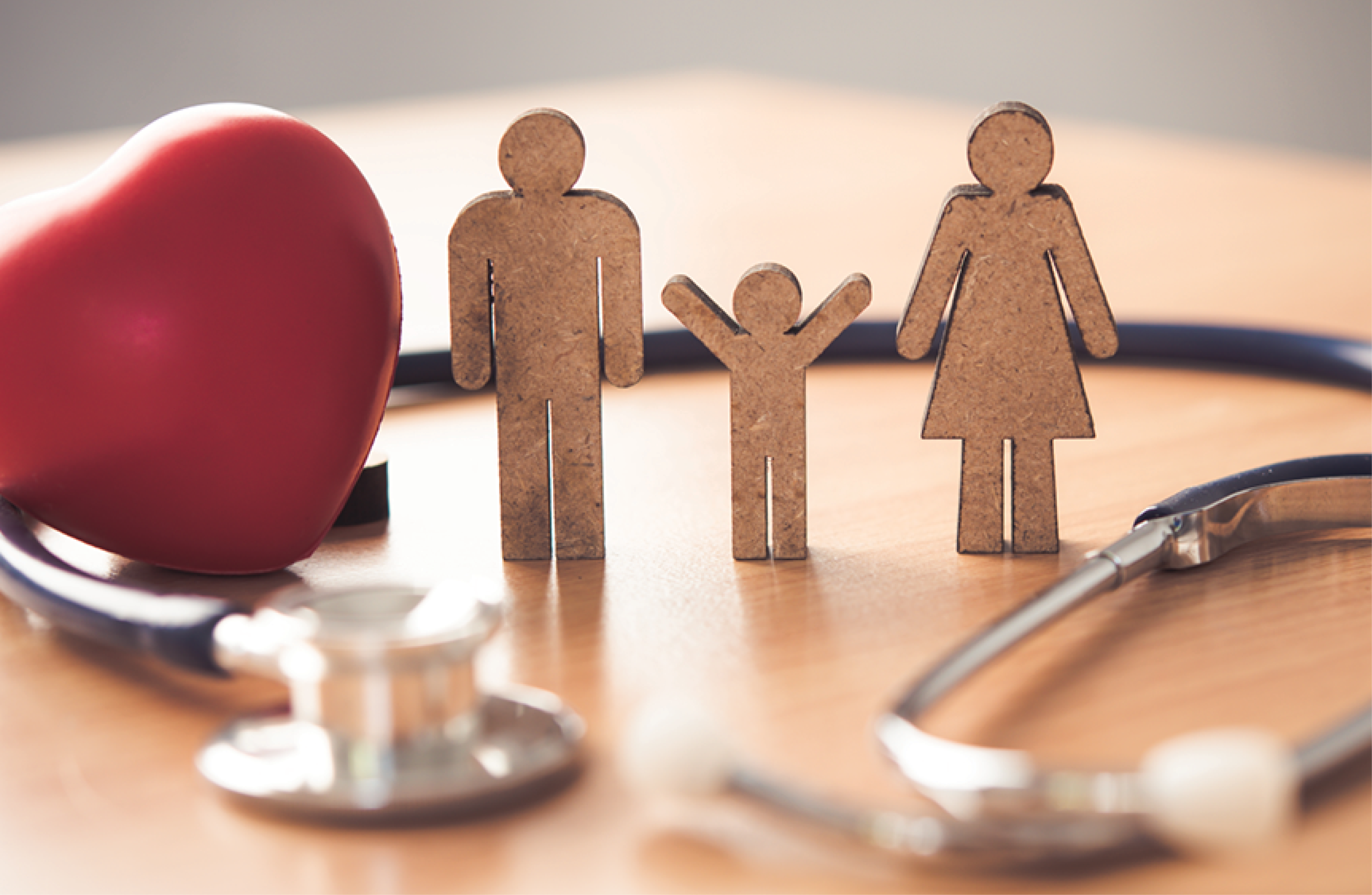 Wooden figures feature a father, mother and child near a stethoscope and heart-shaped object.