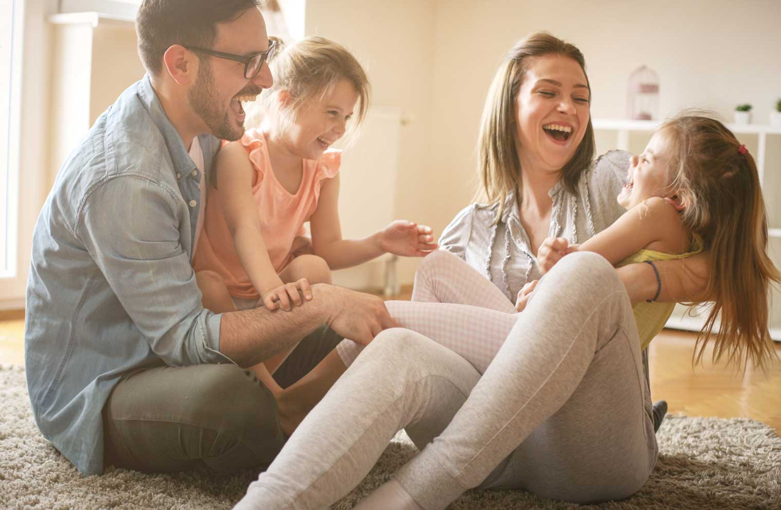 Image of a husband and wife laughing next to each other with children in laps