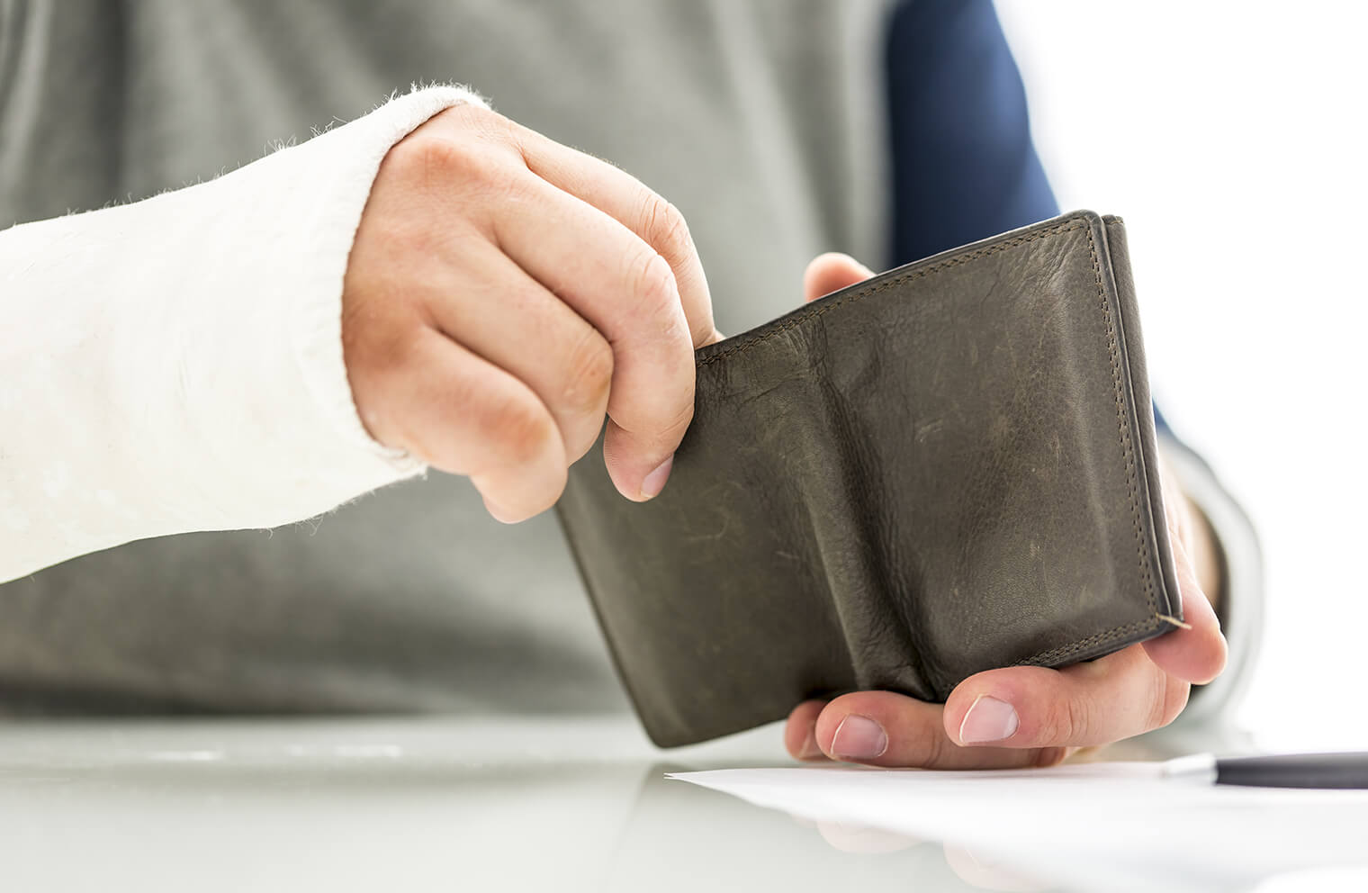 A man with a broken arm opens a wallet. 