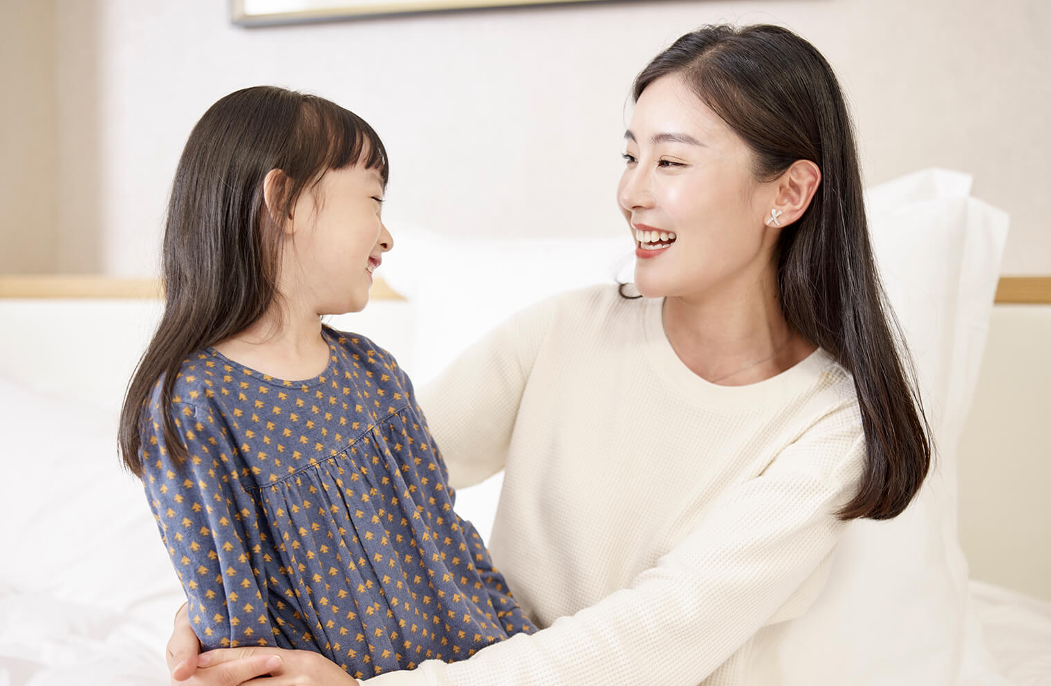 A mother smiles at her young daughter. 