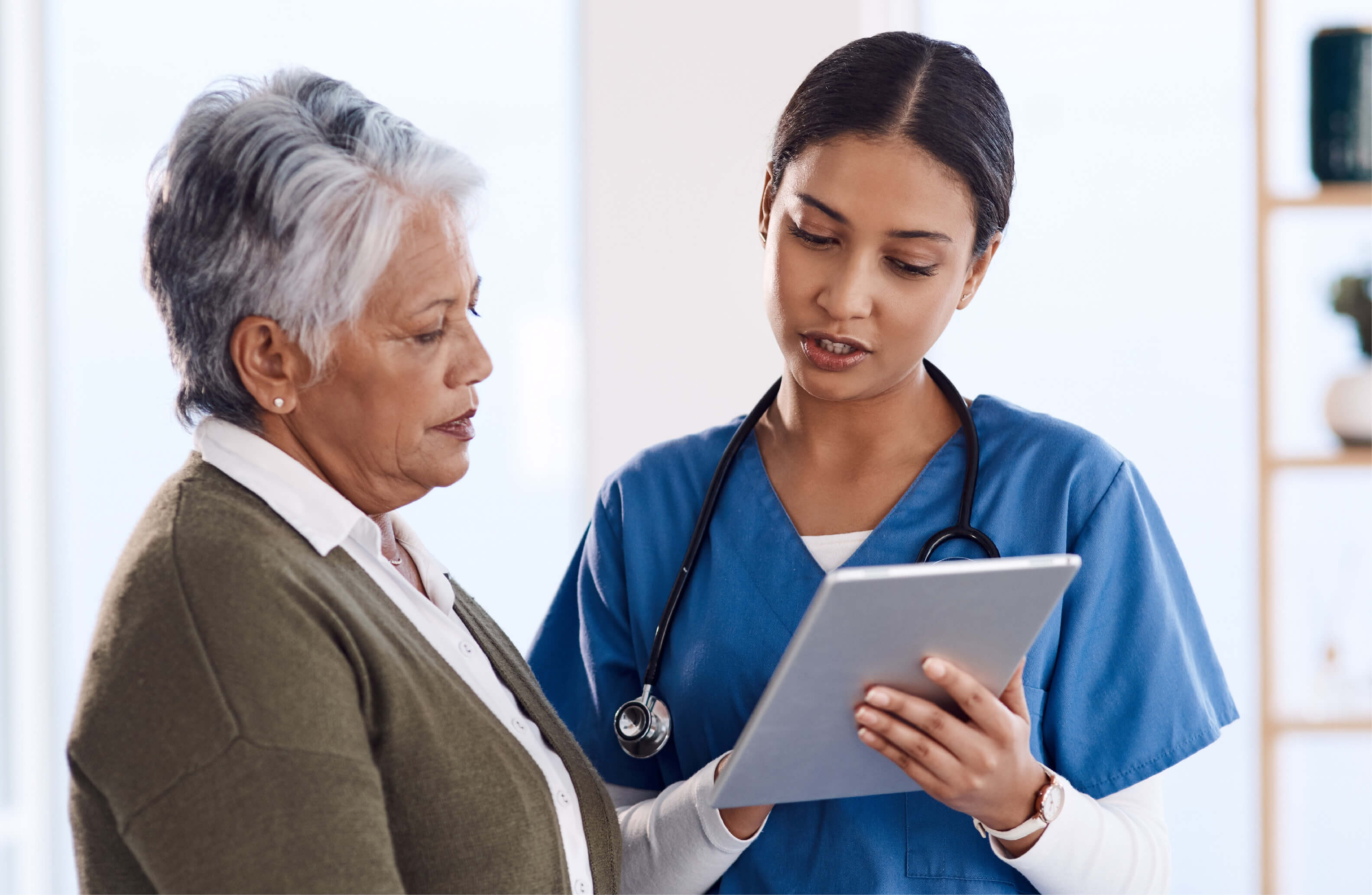 Picture of female nurse reading a tablet to an elderly patient