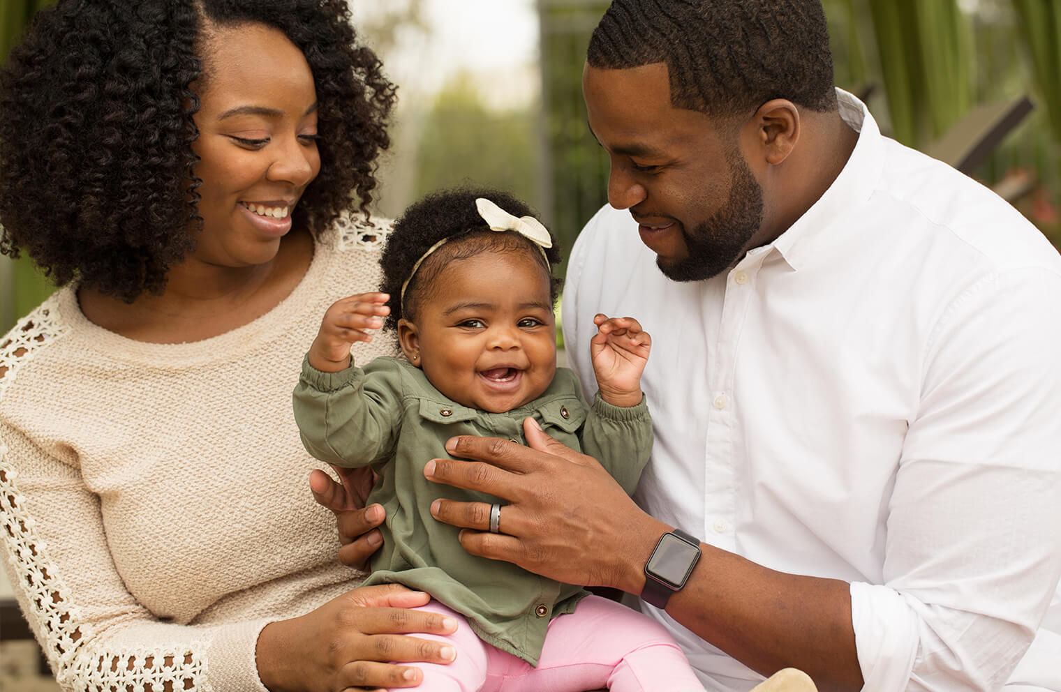 A mother and father hold their happy baby girl. 