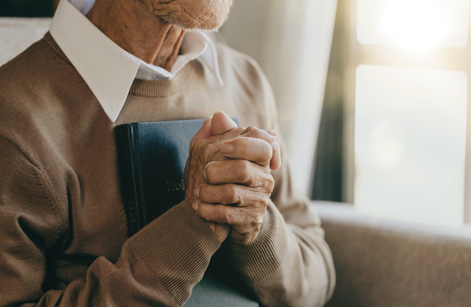 an older man clutching a Bible to his chest
