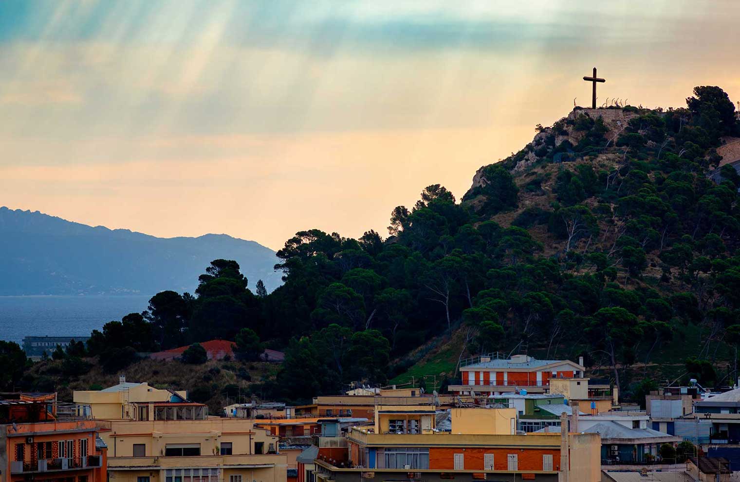 A cross on a hill overlooking a city