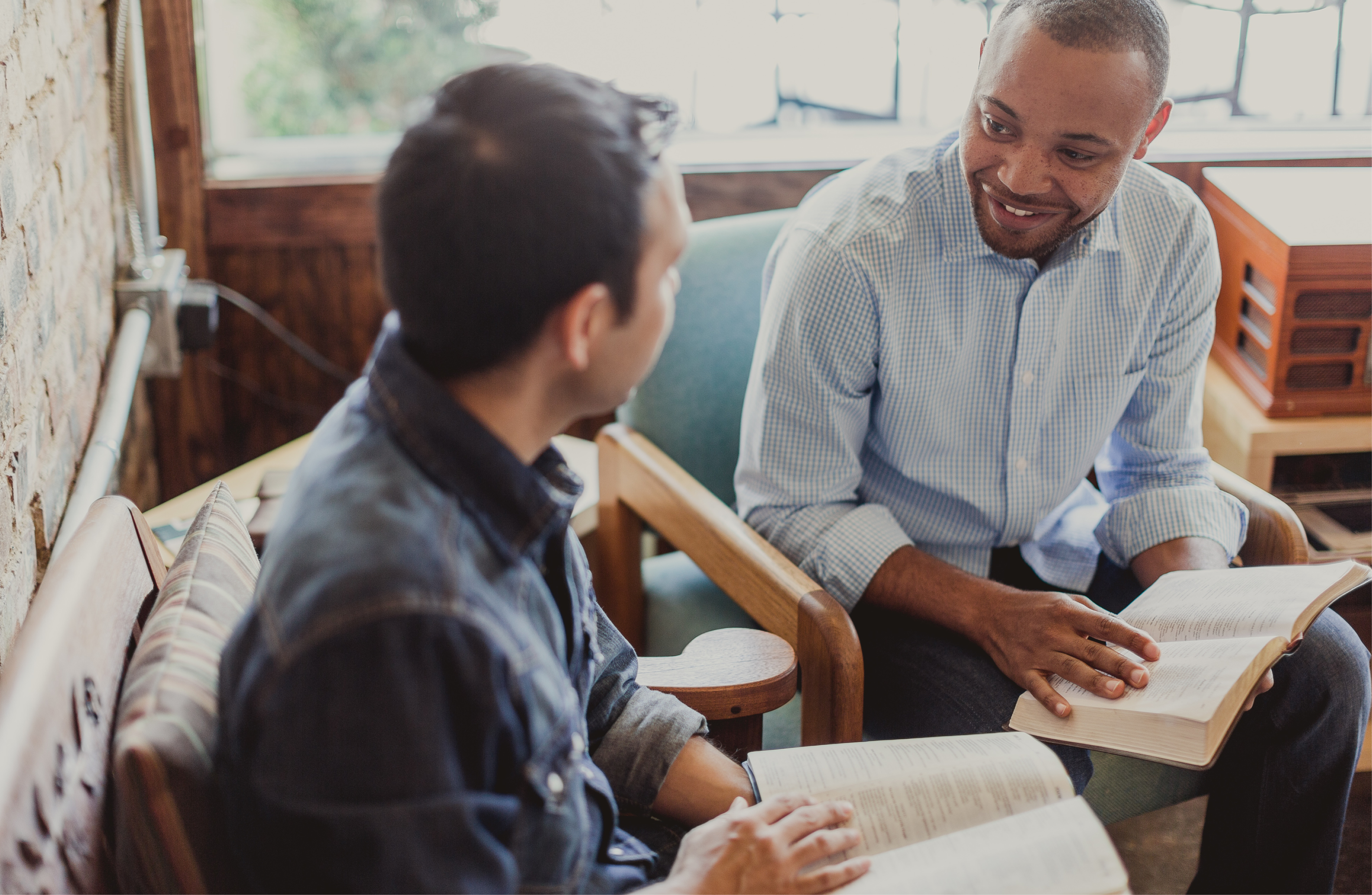 Two men sit together with open Bibles as they discuss church risk management.