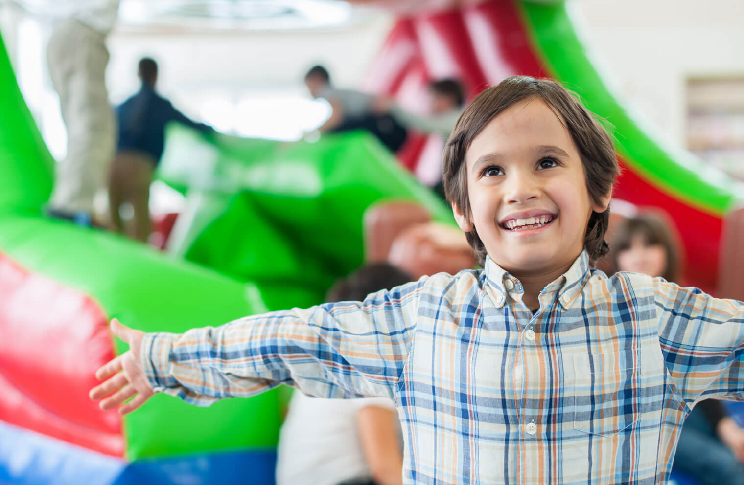 Picture of a child smiling while playing at a bounce house.