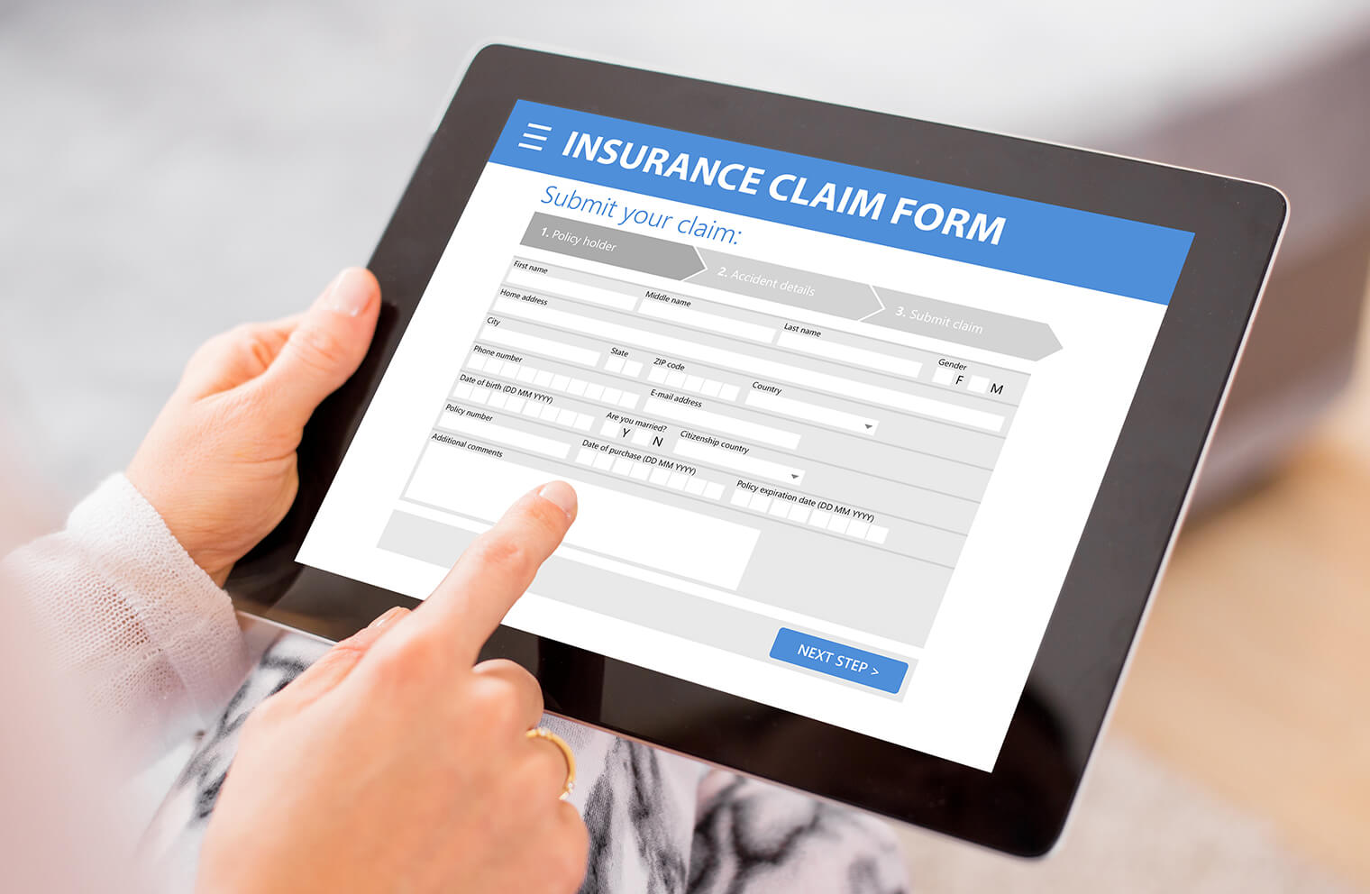 Close up picture of a woman's hands, using a tablet, completing an insurance claim form.