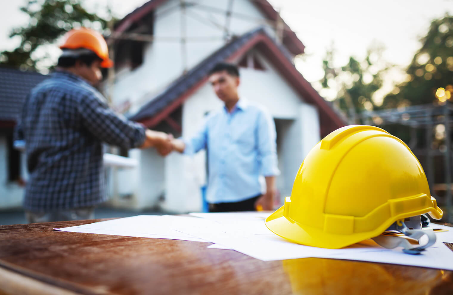 A construction manager shakes hands with a pastor in front of a church.