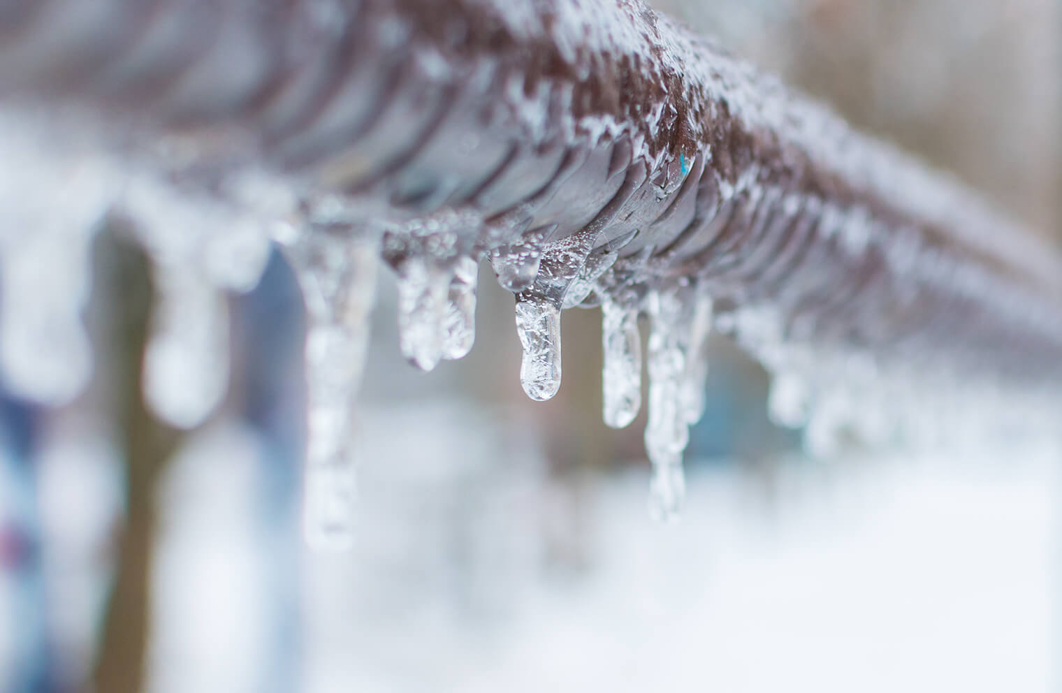 Close up picture of icicles melting off of a gutter.
