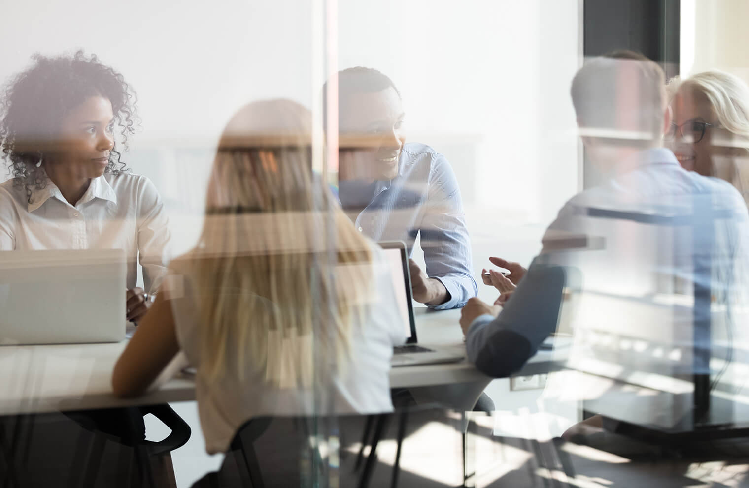 Picture of people in a conference room meeting together on the other side of a glass divider.