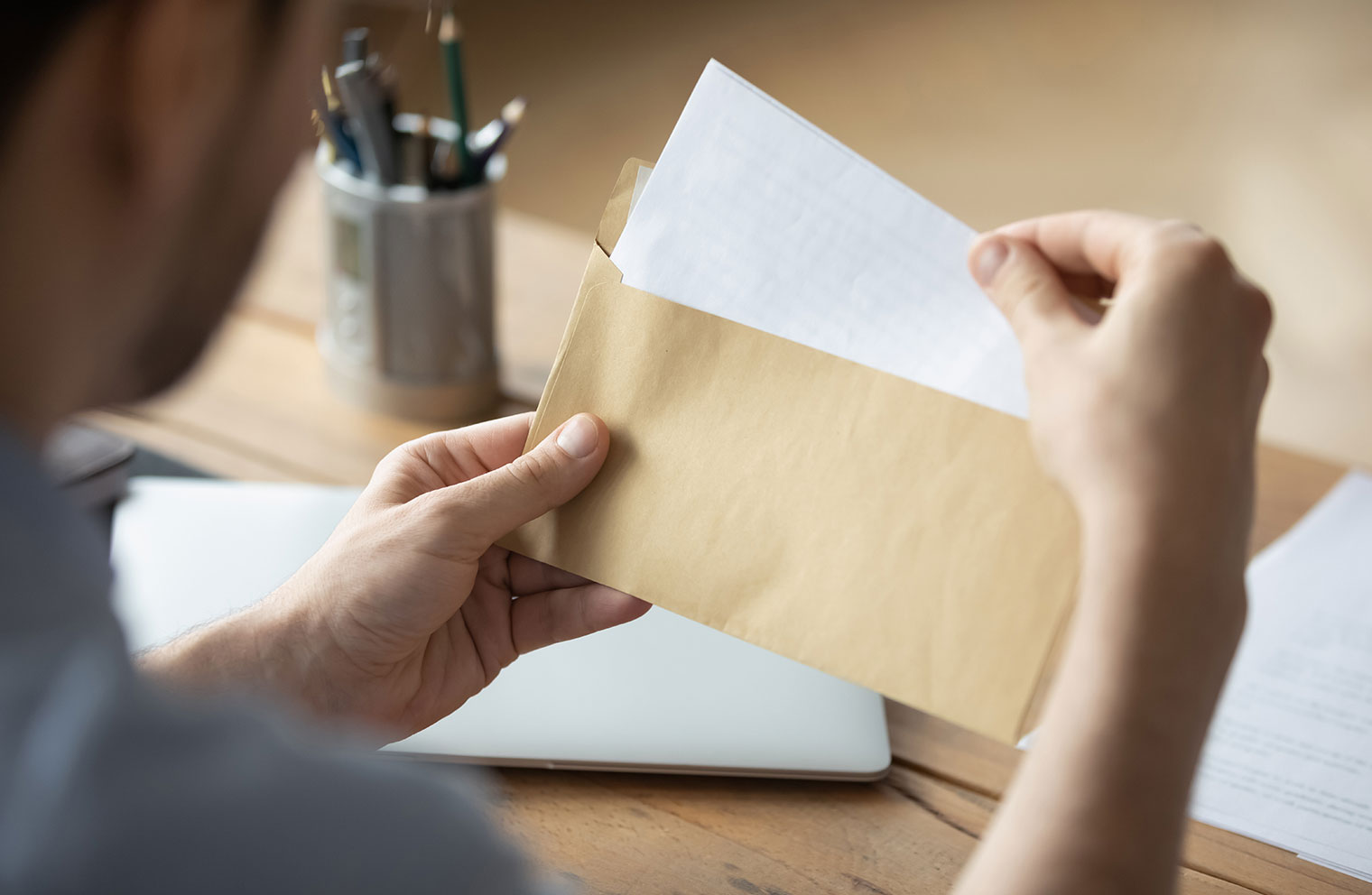 Image of man opening an envelope at desk.