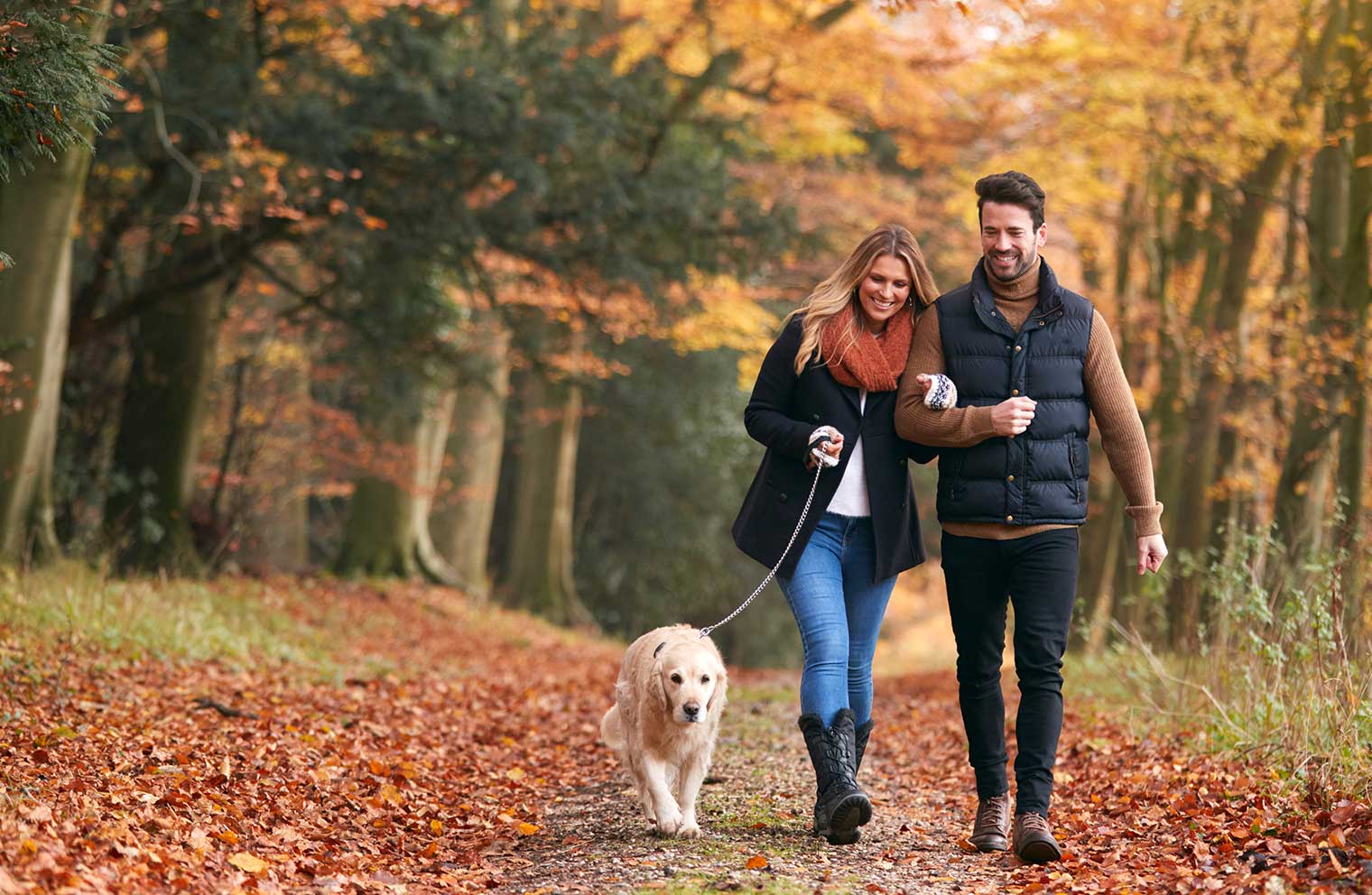 Young couple walking a dog in Fall