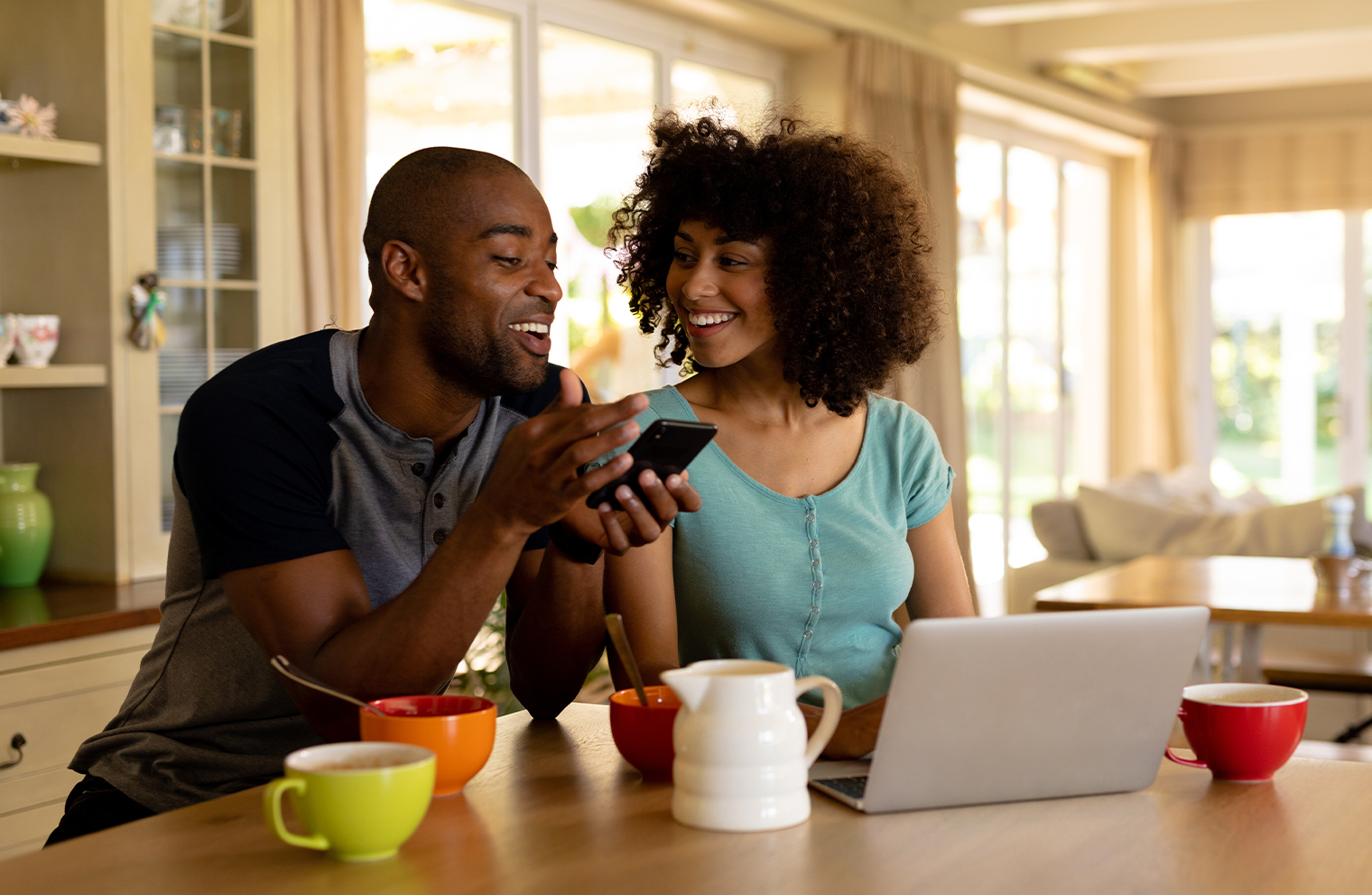 A young couple planning retirement on their laptop at a kitchen counter