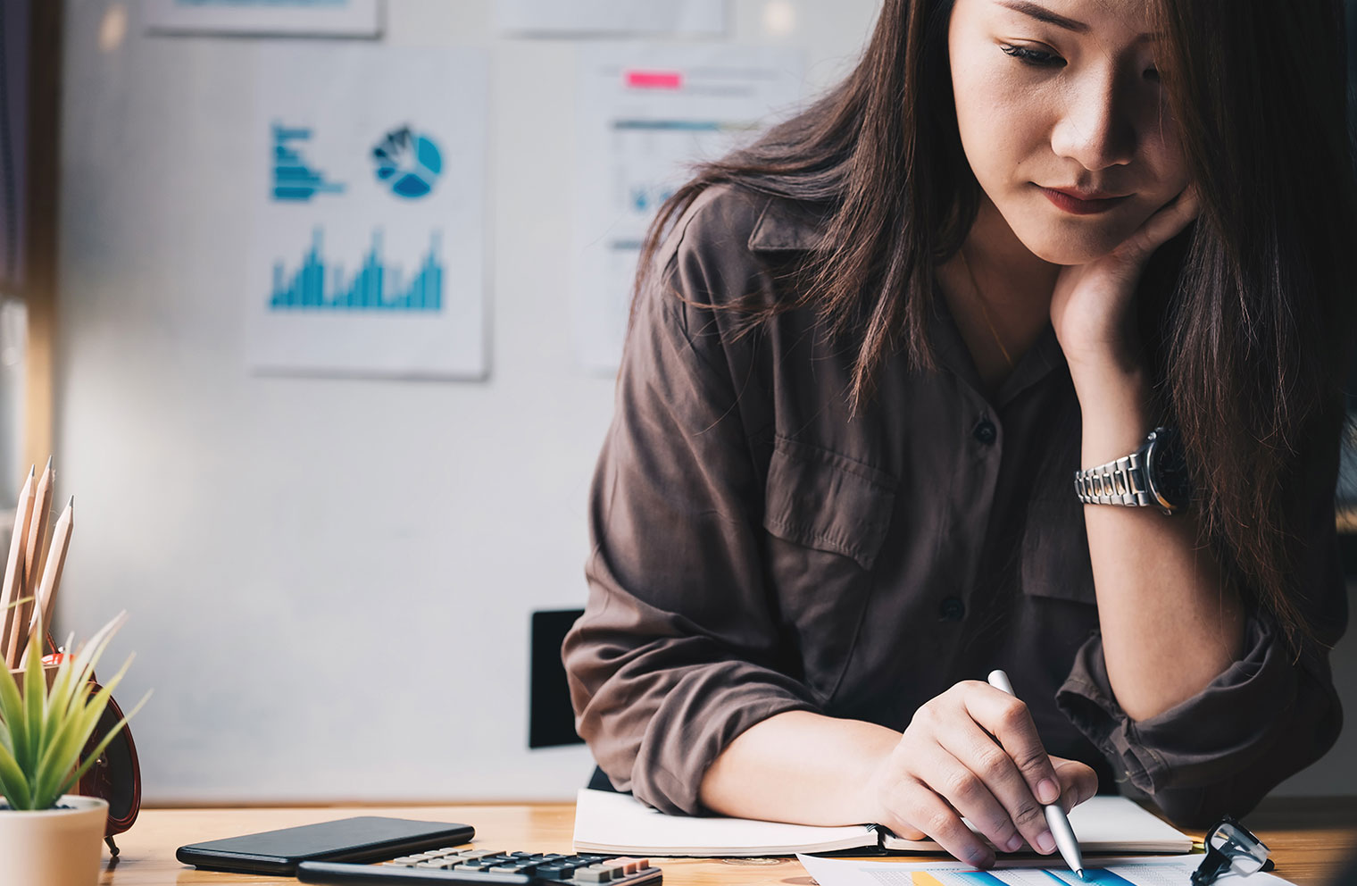 Woman analyzing paperwork sitting at desk.