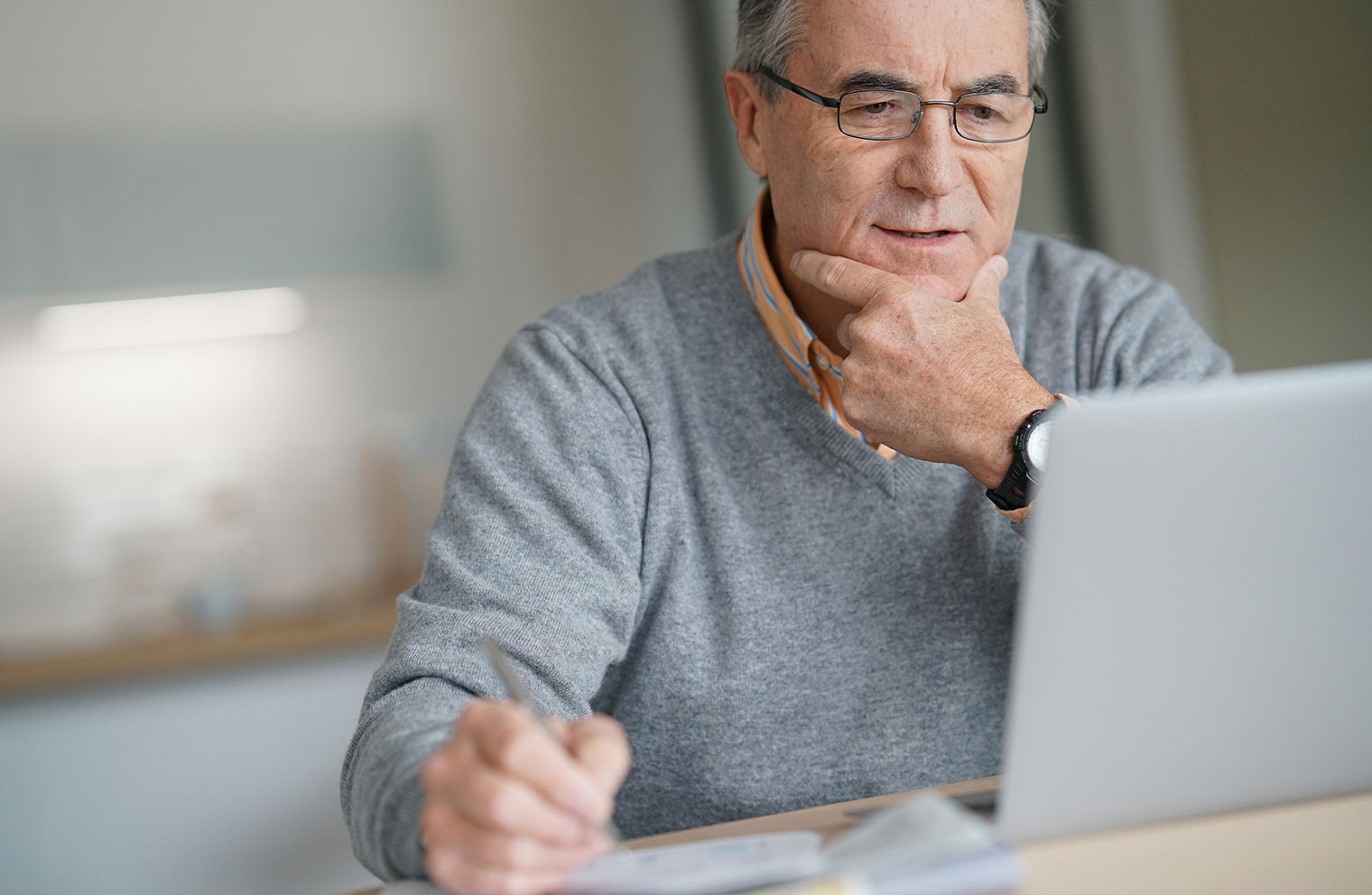 Man sitting at desk looking intently at laptop.