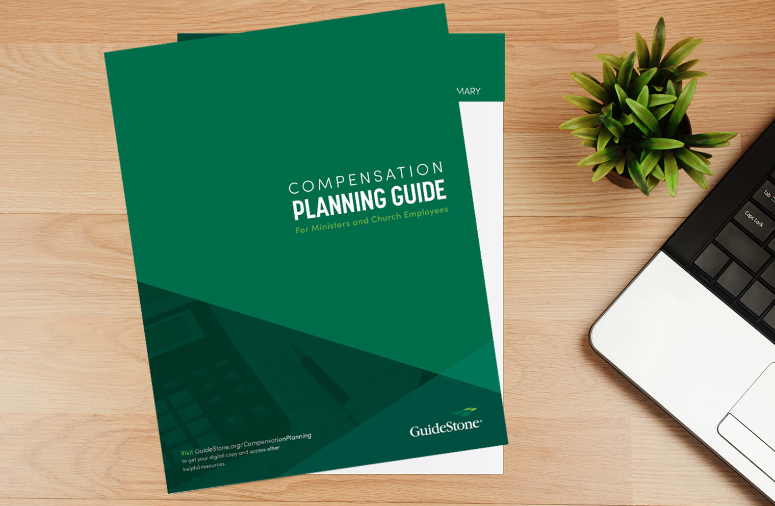 Picture of a compensation planning guide document next to a plant and a laptop on a desk.