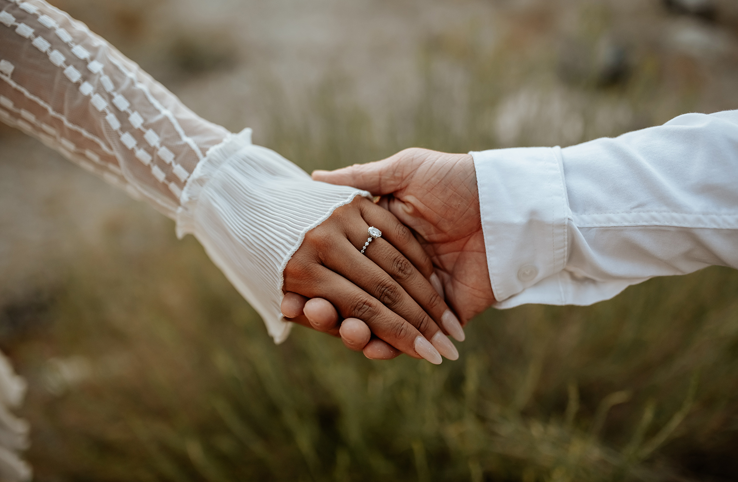 close up view of a couple holding hands with a wedding ring visible