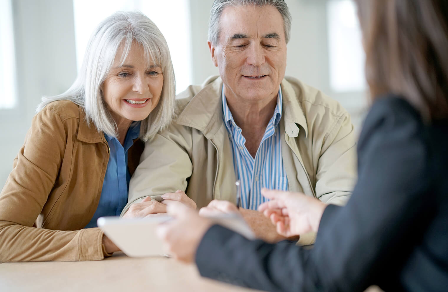 Picture of older couple talking with an advisor and reviewing a tablet.