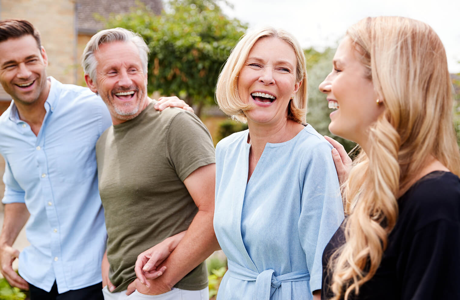 Picture of a retirement-age couple with their adult children, smiling outside.