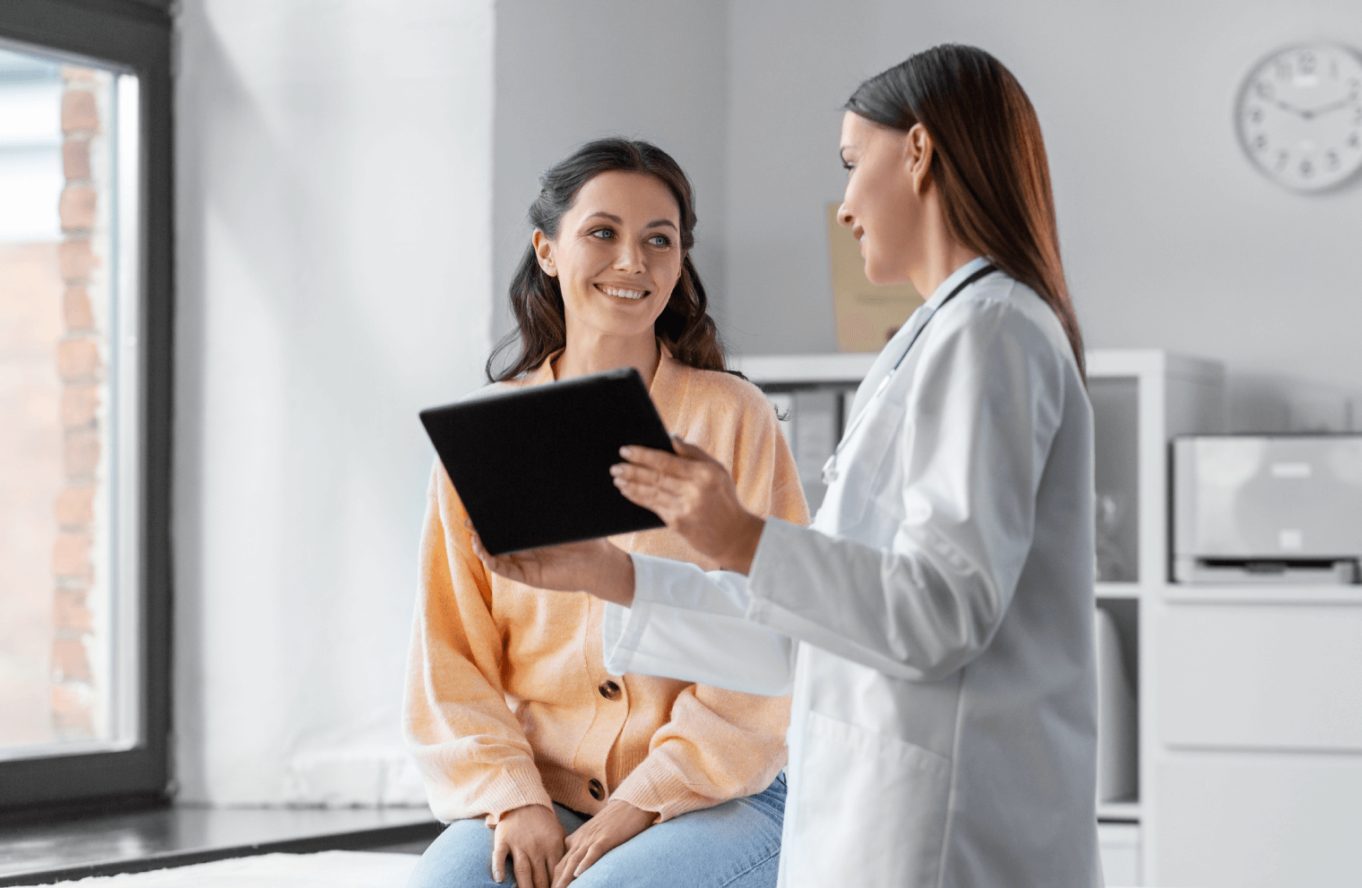 Picture of a doctor holding a tablet while discussing something with her patient.